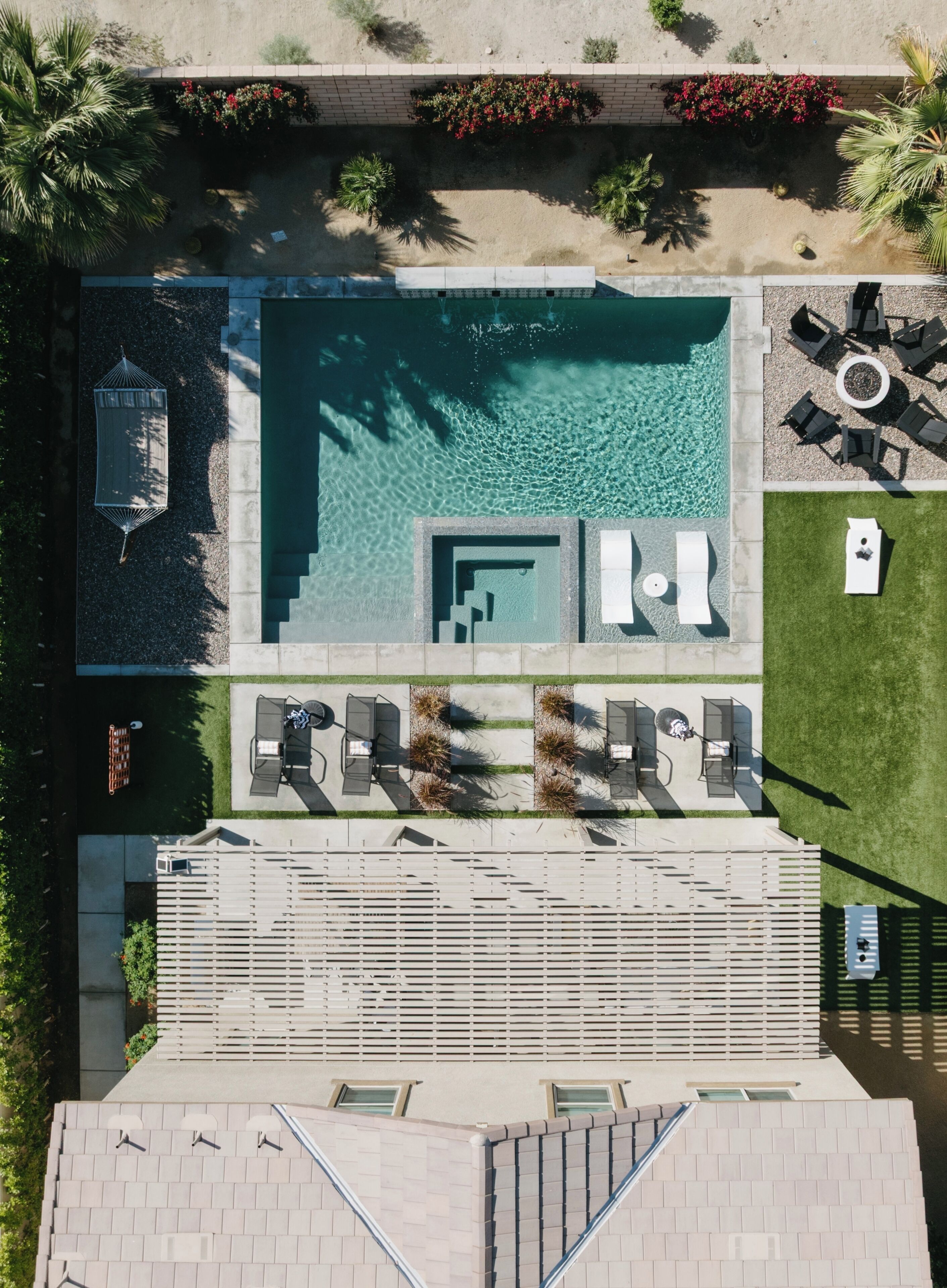 Vue aérienne d’un complexe hôtelier doté d’une piscine, de chaises longues, d’un espace barbecue et d’un patio couvert.