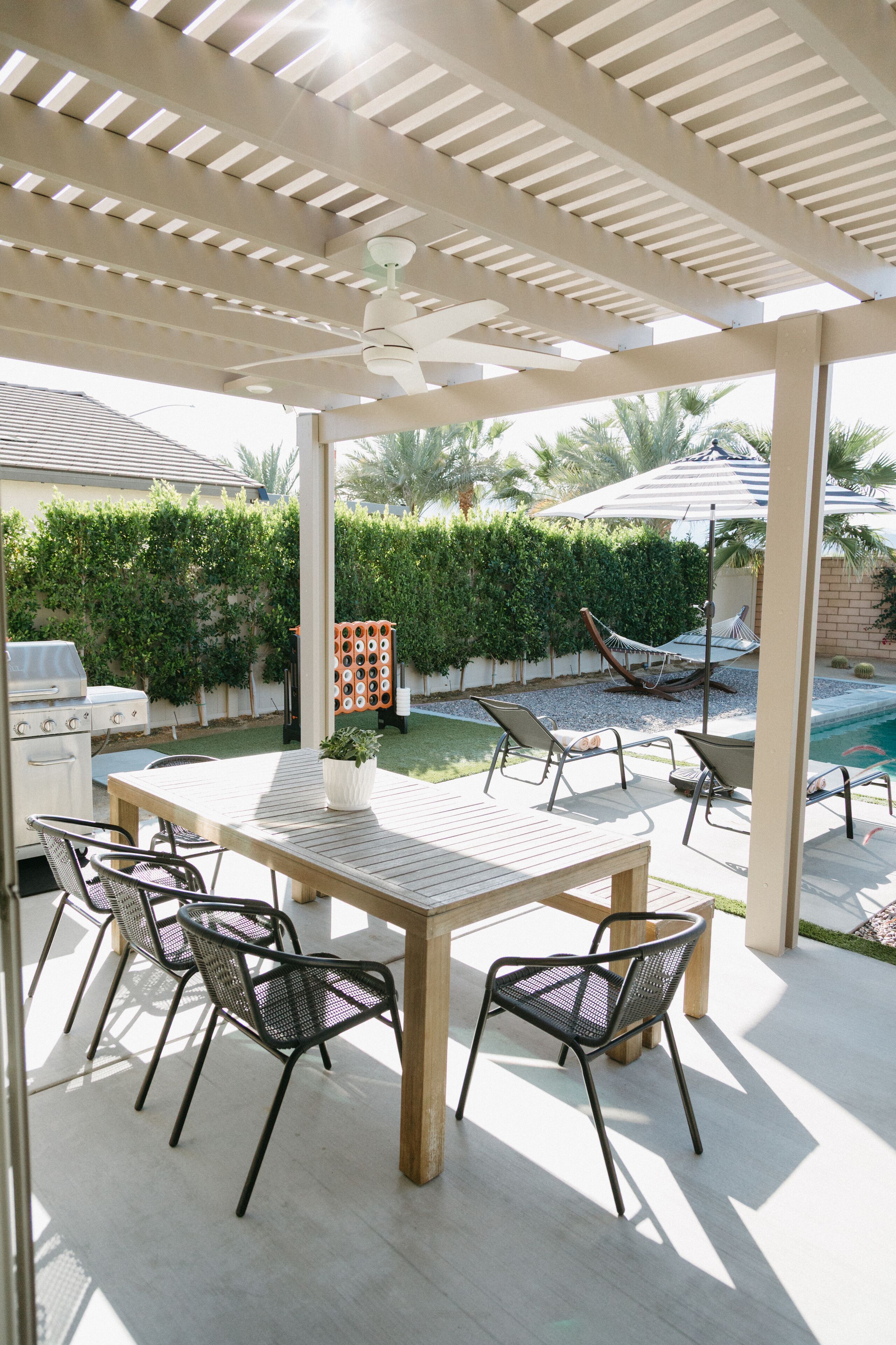 A covered patio with a pool, outdoor furniture, and a grill area.