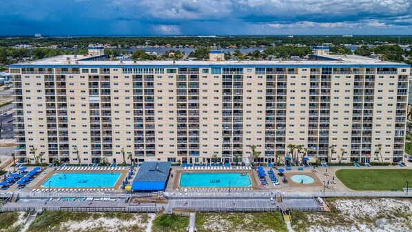 A large hotel with multiple floors, a rooftop pool, and a beach area with sun loungers.