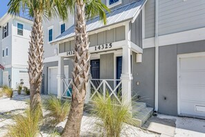 Une propriété située en bord de mer, avec une façade blanche, portant le numéro 14325, et comprenant une véranda couverte et un garage.
