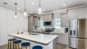 A modern kitchen with a central island, stainless steel appliances, and bar stools. - Premium Pet Friendly Townhouse at Lost Key Resort | Balcony w/Gulf Views | Beach Club |Pools (Pensacola)