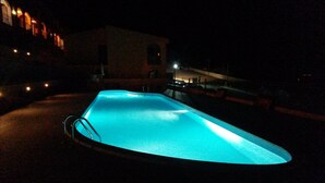 Una piscina di notte con bordo trasparente e una scaletta.