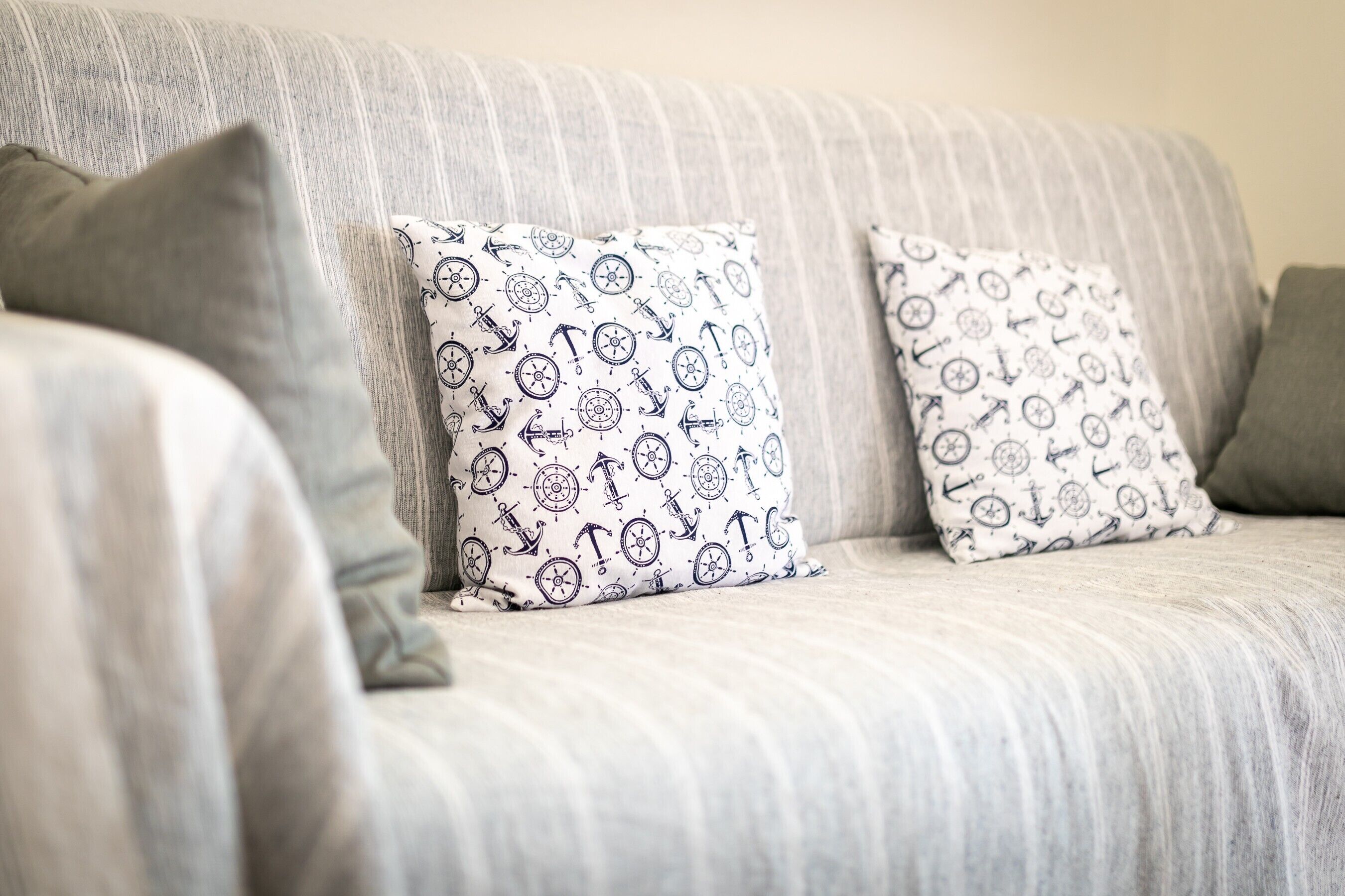 A striped sofa with two patterned pillows and a grey pillow.