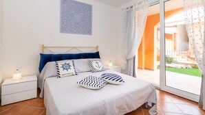 Una camera da letto con un letto, comodini, un elemento decorativo a parete e vista attraverso una porta vetrata.