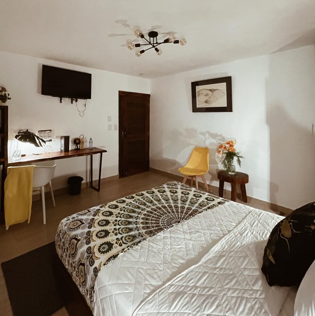 Ein Schlafzimmer mit einem Bett, einem Schreibtisch, einem Sessel, einem Fernseher und einem Deckenventilator.