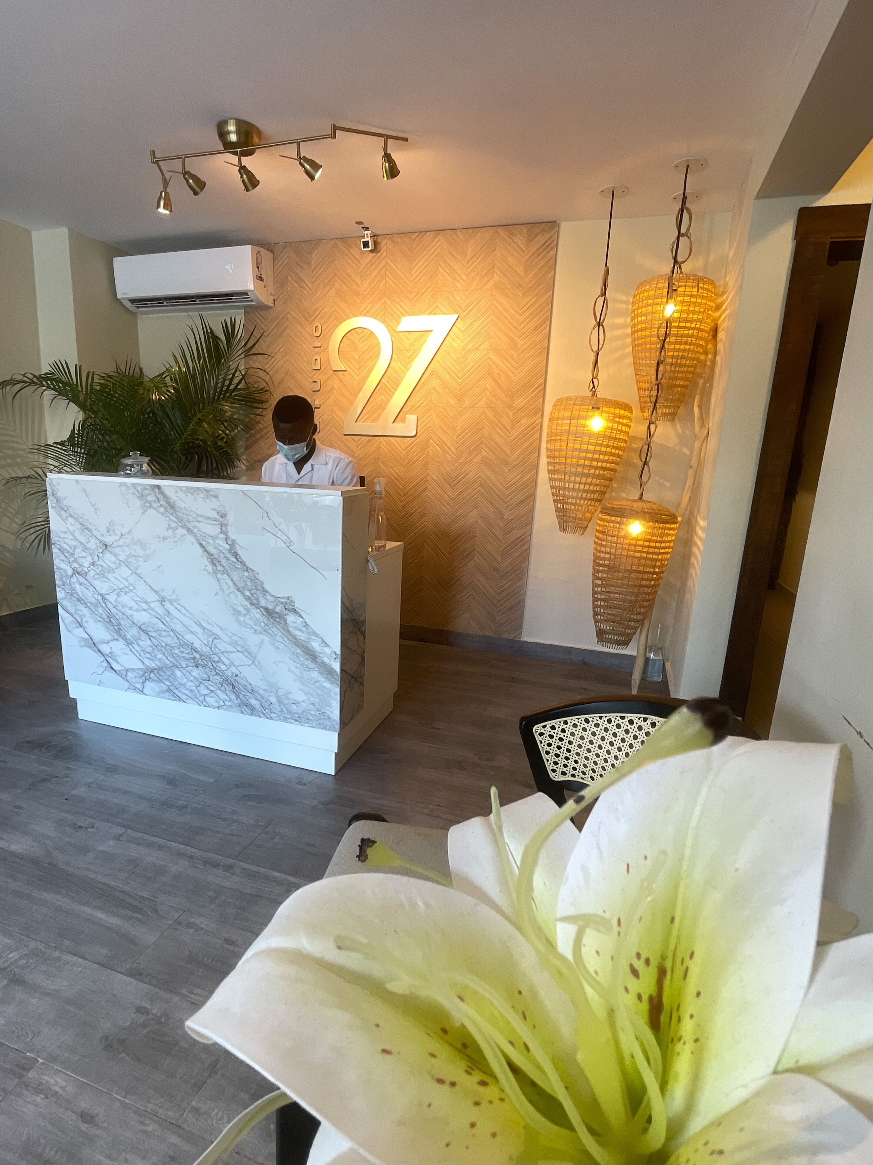 A reception desk with a marble top, a large number '27' on the wall, and a hanging light fixture.
