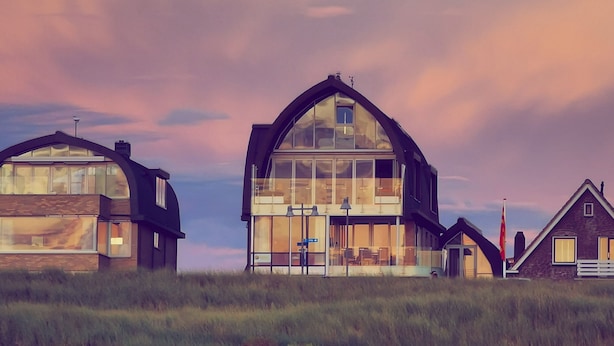 Una casa moderna con amplios ventanales y un diseño de techo curvo y original.