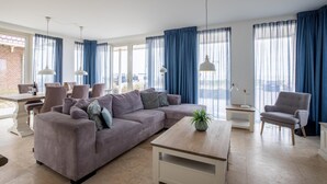 Una sala de estar moderna con un sofá modular, una mesa de centro y un comedor con sillas y una mesa.