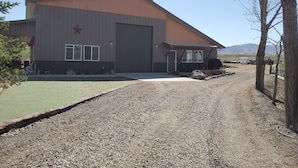 Un edificio industrial grande con una estrella destacada en la fachada, un área cubierta con mesas al aire libre y un camino de grava que lleva a la entrada.