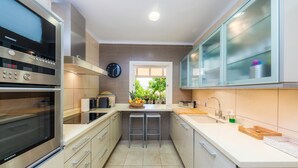 A modern kitchen with a Siemens oven, a microwave, a sink, and a window with a view of greenery.