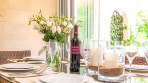 A table set with plates, cutlery, wine, and candles, with a bottle of wine and a vase of flowers.
