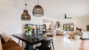 En moderne stue med spiseplads, sofa, sofabord og loftventilator.