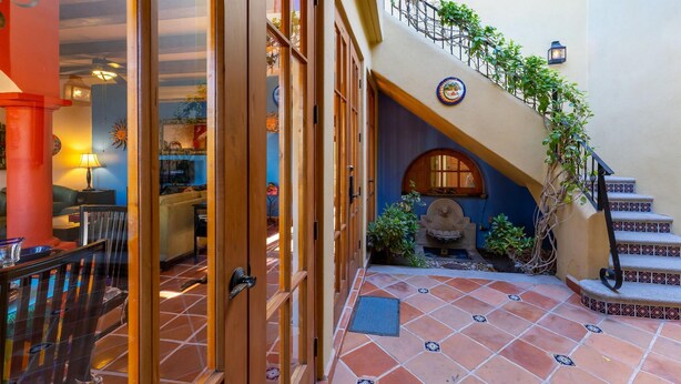 A spacious hallway with a tiled floor, a staircase with a decorative railing, and a view of the interior space. - Casa Juanchi by Casago (Loreto)