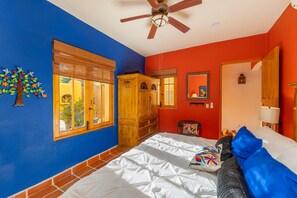 Ein Schlafzimmer mit Bett, Deckenventilator, Fenster und Holzschrank.