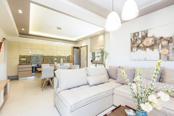 A modern living room with a sofa, a coffee table, and a dining area with chairs.