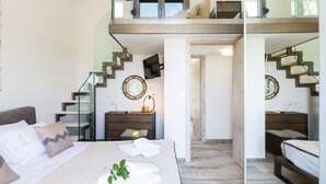 A modern bedroom with a bed, bedside tables, a mirror, and a staircase. - Luxury Villa set in nature with private pool (Rethymno)
