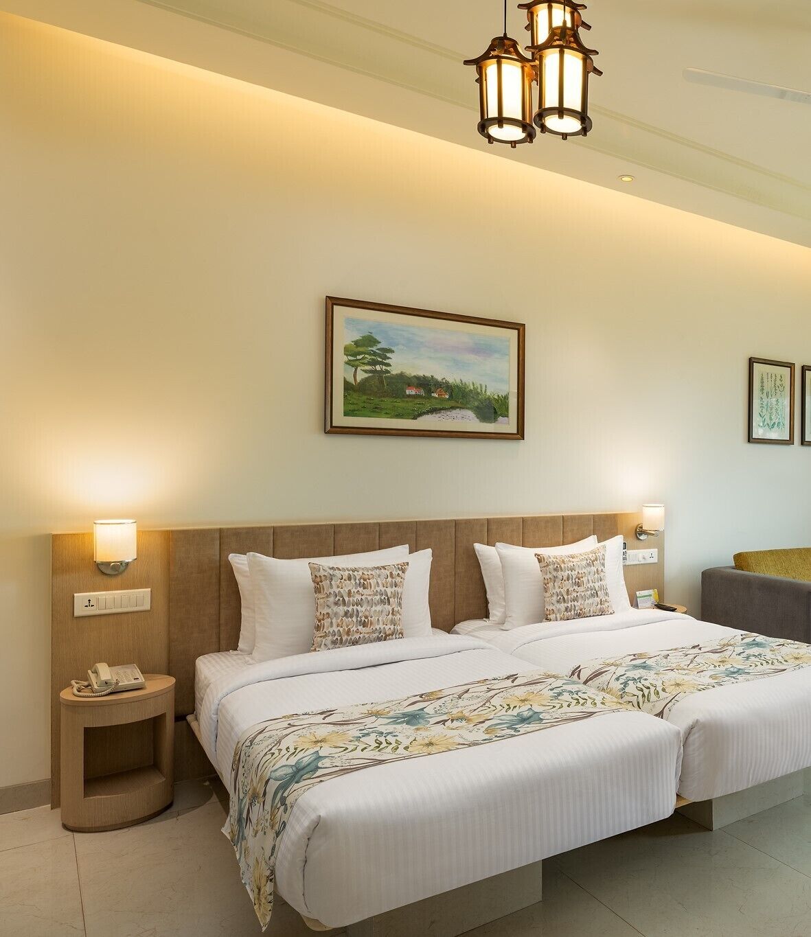 A hotel room with a large bed, two bedside tables, a nightstand, a painting, and a ceiling light fixture.
