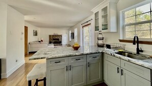 Une cuisine moderne avec des meubles de couleur claire, un plan de travail en marbre et une grande fenêtre qui laisse entrer la lumière naturelle.