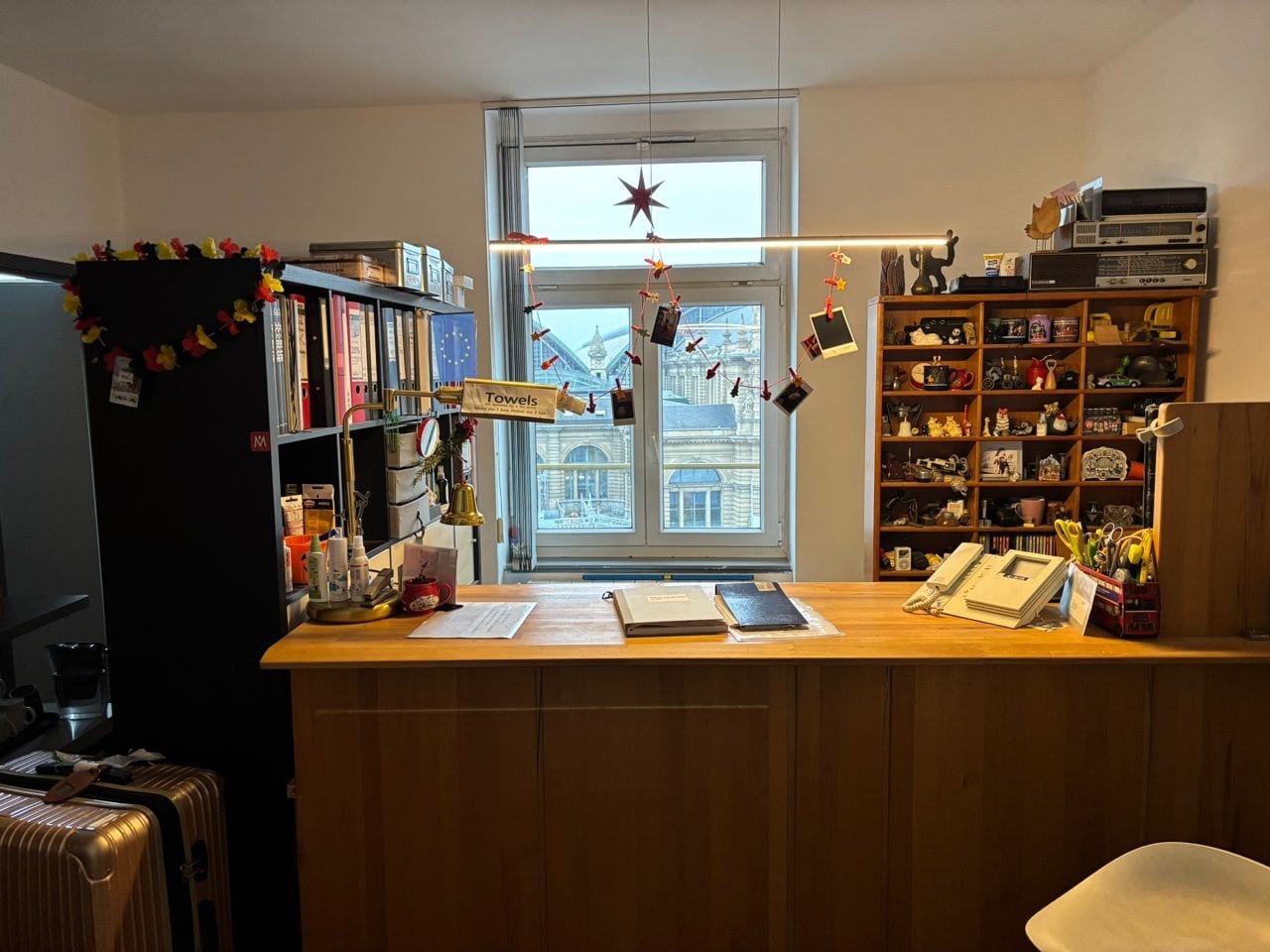 Una oficina en casa con un escritorio, estanterías, un ventanal decorado con una estrella y vistas a un paisaje urbano.