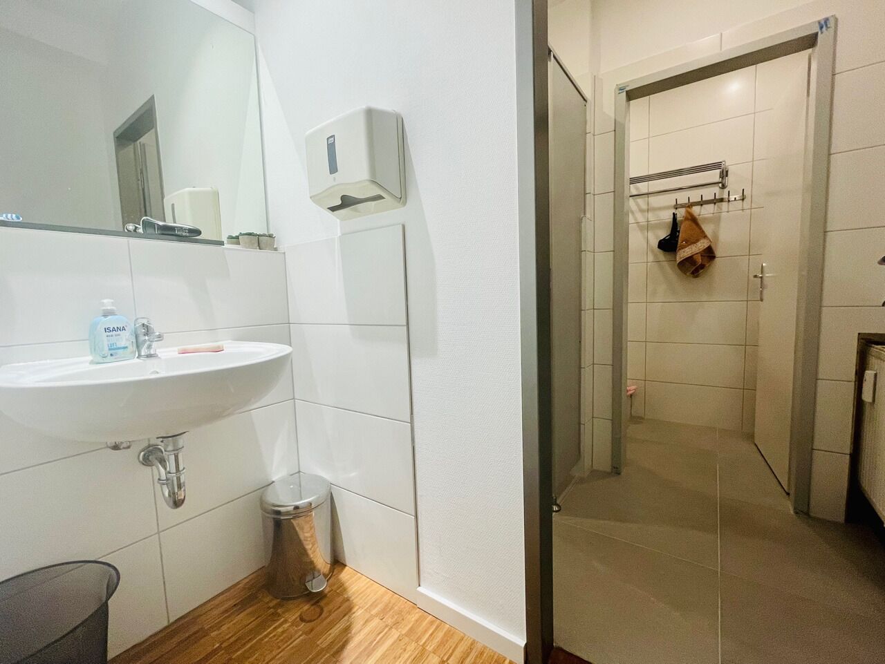 Un baño con lavabo, espejo, secador de manos y toallero.