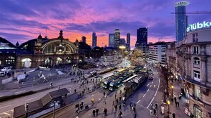 A cityscape with a prominent train station, modern high-rise buildings, and a tram system. - JC&BLUE Guesthouse - Hostel (Frankfurt)