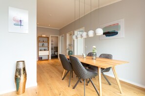 Un espace de salle à manger moderne avec une table en bois, des chaises noires et des luminaires suspendus.