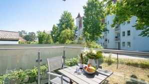 A balcony with a table, chair, and a bowl of fruit. - Villa Maxim, App. 2, Germany (Heringsdorf)