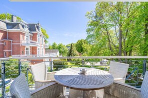 A balcony with wicker furniture and a view of a red brick building.