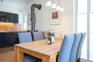 Een moderne keuken met donkere kastjes, een houten eettafel en blauwe stoelen.