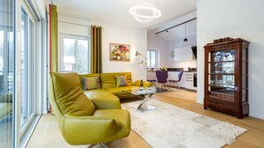 Ein modernes Wohnzimmer mit einem grünen Sofa, einem Glastisch und einer Holzkassette.