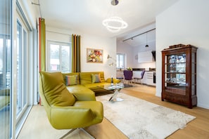 Uma sala de estar moderna com um sofá verde, uma mesa de centro de vidro e um armário de madeira.