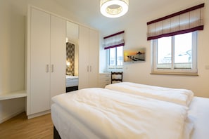 A bedroom with a large wardrobe, a bed, and a desk with a chair. - Quartier Eichenweg, App. 8 (Heringsdorf)