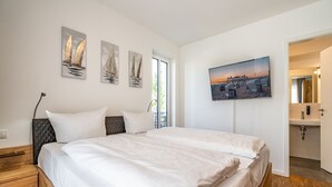 A bedroom with a bed, a nightstand, a TV, and artwork on the wall. - Quartier 7, App. 07, Germany (Heringsdorf)