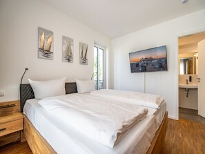 Et soveværelse med en seng, et natbord, et fjernsyn og billedkunst på væggen.