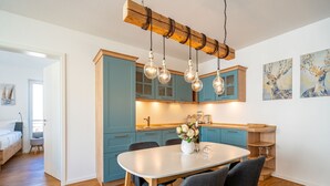 A modern kitchen with teal cabinets, a wooden ceiling, and pendant lights. - Quartier 7, App. 07, Germany (Heringsdorf)