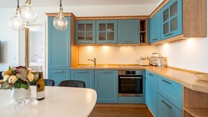 A modern kitchen with blue cabinets, a wooden countertop, and a built-in oven. - Quartier 7, App. 07, Germany (Heringsdorf)