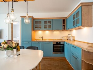 Et moderne køkken med blå skabe, en træbordplade og en indbygget ovn.