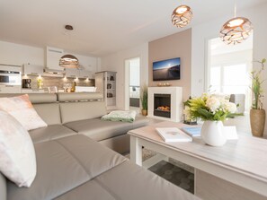 A modern living room with a sofa, a fireplace, and a dining area.