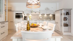 Une cuisine moderne avec des meubles blancs, un îlot central et un luminaire suspendu.