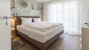 Ein Schlafzimmer mit einem großen Bett, einem Nachttisch, einer Lampe und Wandgemälde.