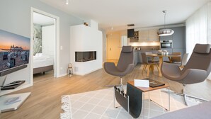 Ein modernes Hotelzimmer mit Bett, Sitzgelegenheit, Küchenzeile und Kamin.