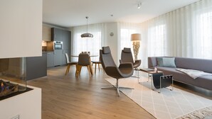Ein modernes Wohnzimmer mit einer Couch, Sesseln, einem Kamin und einem Essbereich mit Tisch und Stühlen.
