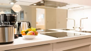 Uma cozinha moderna com eletrodomésticos de aço inoxidável, bancada branca e uma tigela de frutas.
