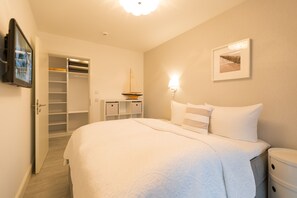 Ein Schlafzimmer mit einem großen Bett, einem Nachttisch, einem Schrank und einem an der Wand befestigten Regal.