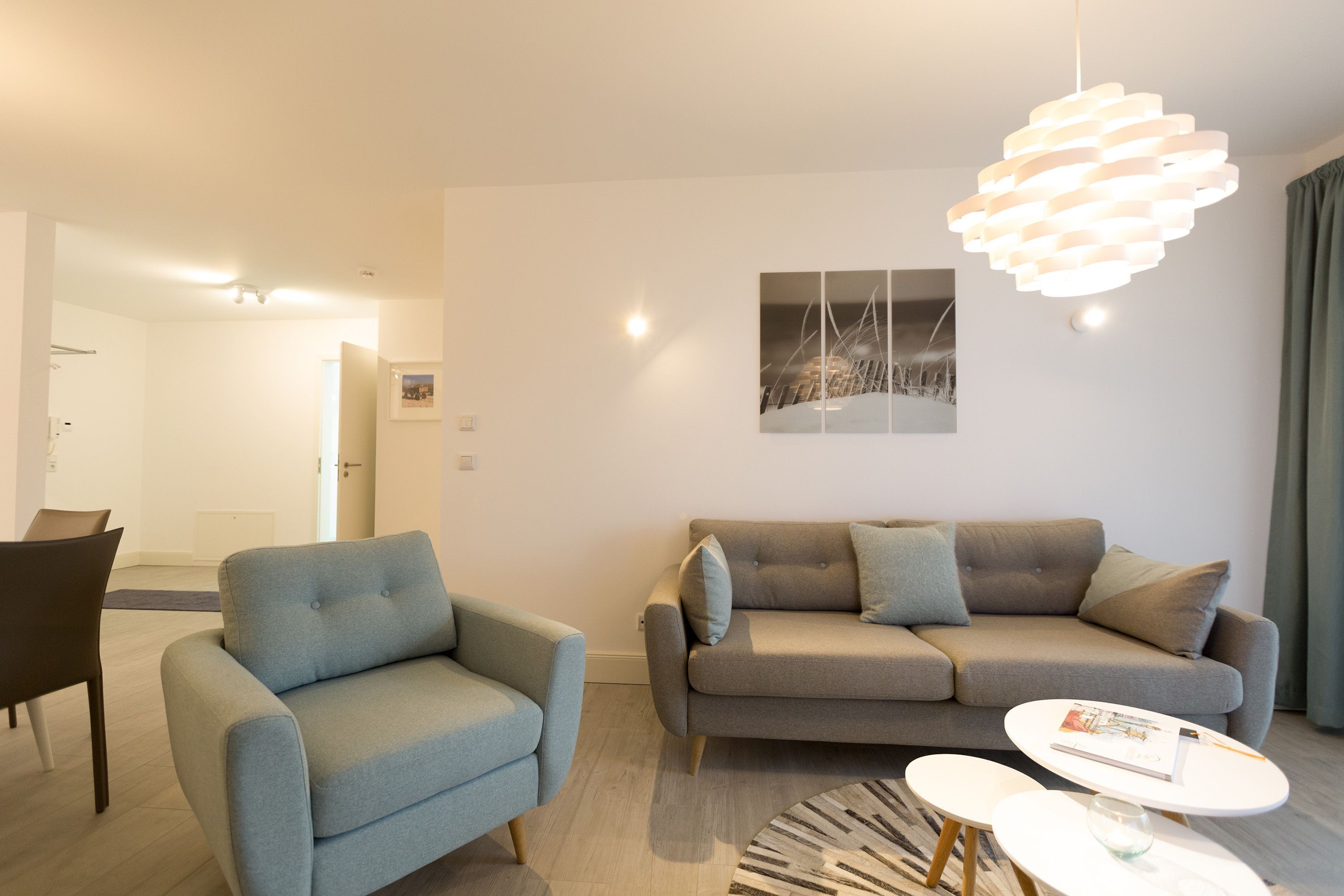 A modern living room with a grey sofa, a blue armchair, and a white coffee table.