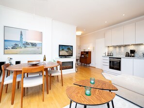 A modern living room with a dining area, a kitchen, and a fireplace. - Villa Vineta, App. 10 (Heringsdorf)