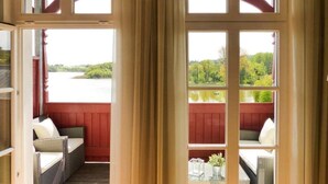 Una stanza con vista su un lago e una foresta, con una panca di legno rossa e mobili in vimini.