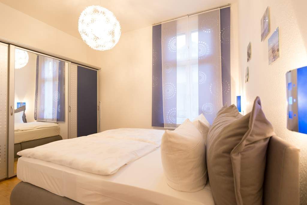 A bedroom with a bed, a wardrobe, and a large window with a view.