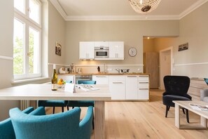 A modern kitchen with white cabinets, a central island, and a dining area with blue chairs.