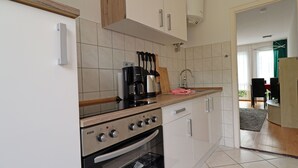 Een moderne keuken met witte kastjes, een ingebouwde oven en een koffiezetapparaat.